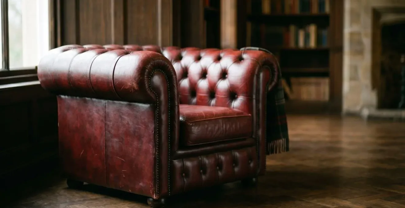Close-up detail of hand-stitched leather seams on a traditional British upholstered armchair showing artisan craftsmanship