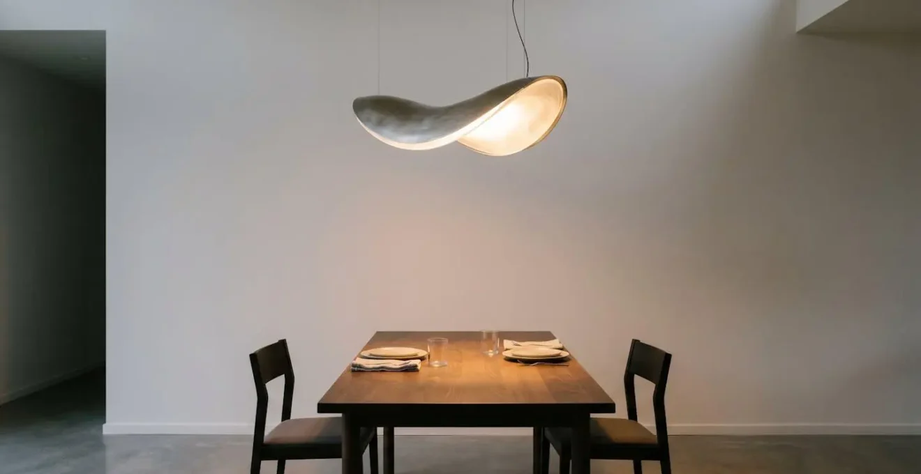 Elegant sculptural pendant light with warm glow illuminating dining table in modern interior