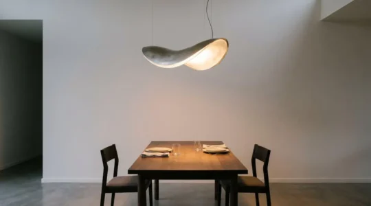 Elegant sculptural pendant light with warm glow illuminating dining table in modern interior