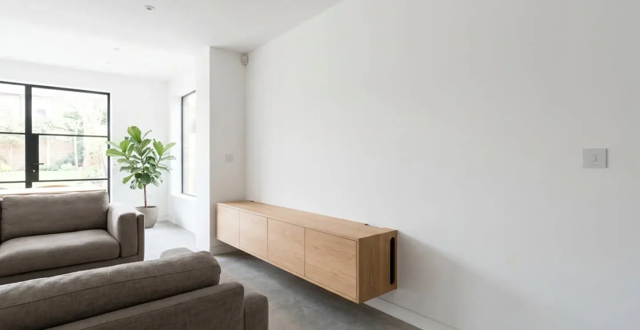Clean UK living room interior showing invisible smart home integration with recessed outlets hidden cables and paintable motion sensors blending seamlessly
