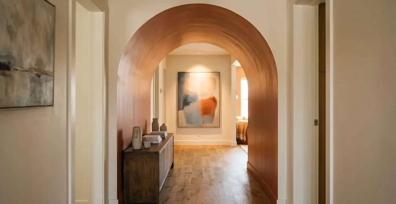 Hallway featuring a statement arch with strategic paint sheen and lighting creating depth perception rather than visual obstruction