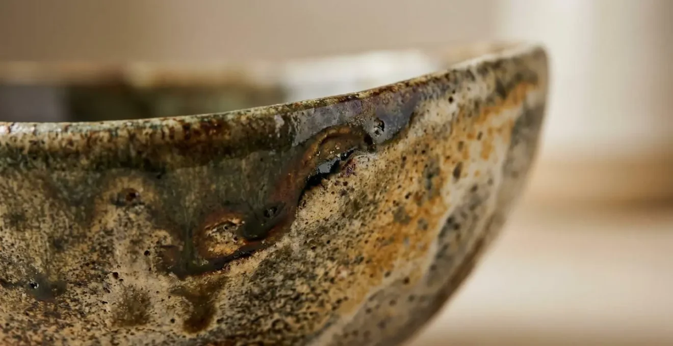 Extreme close-up of a ceramic decorative bowl showing surface texture, glaze variation, and tactile density that creates visual weight