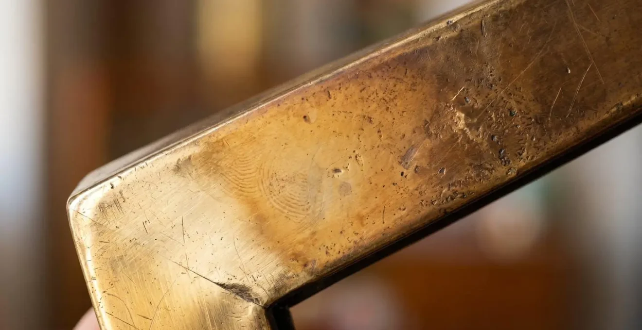 Extreme close-up macro photograph showing the evolving patina spectrum on unlacquered brass surface from bright gold to warm honey tones